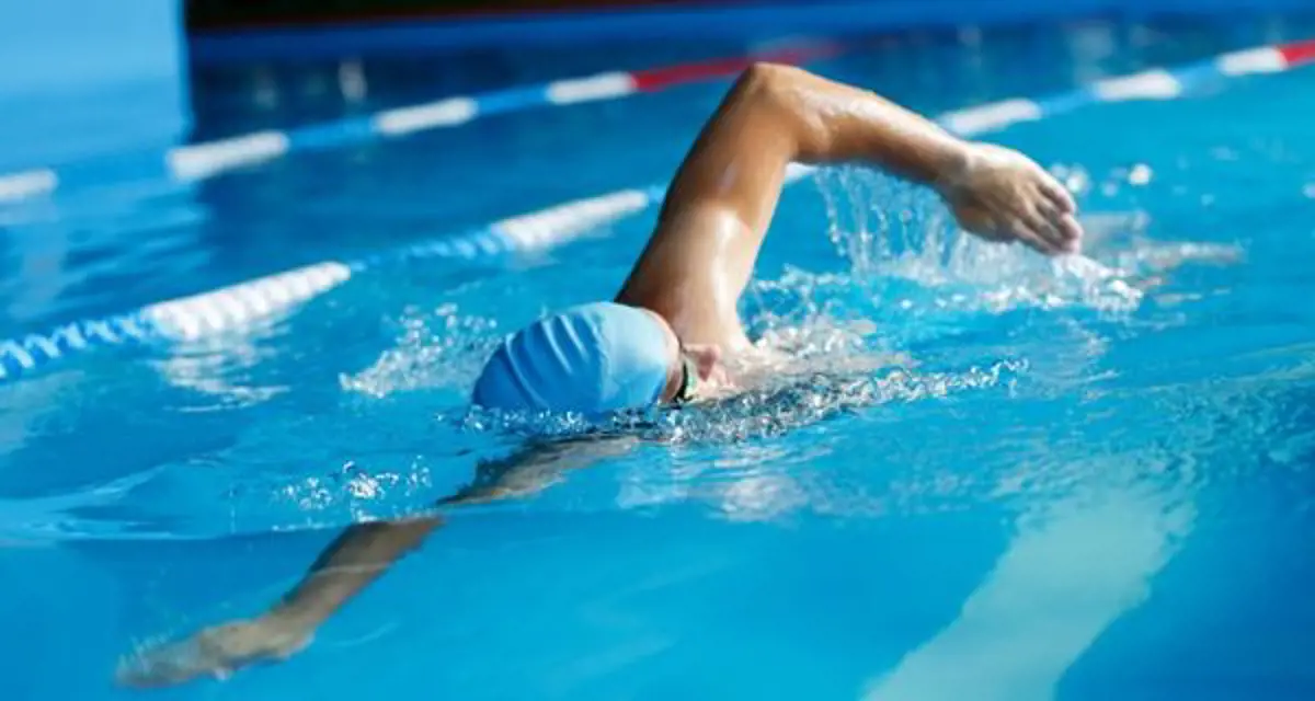 A person in a blue swim cap swimming laps at Christchurch Recreation and Sport pool.