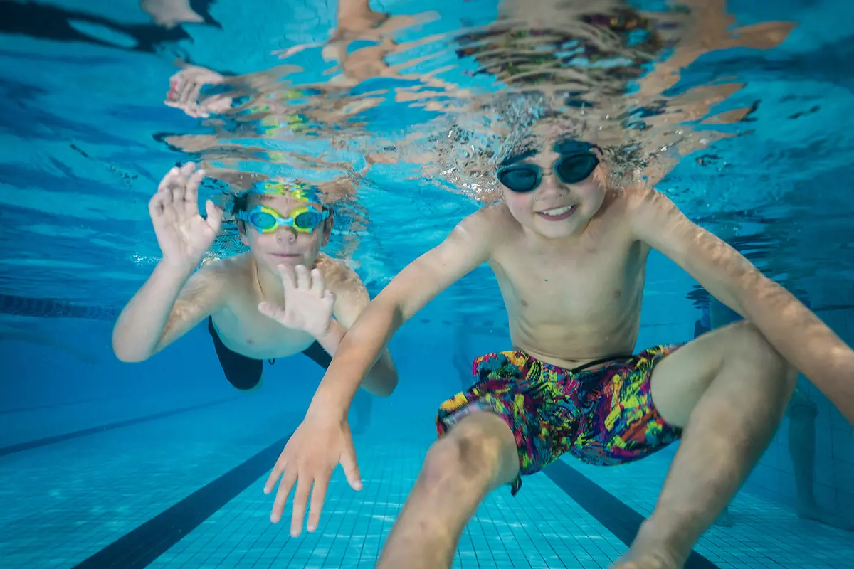 Two smiling boys underwater at Christchurch Recreation and Sport pool.