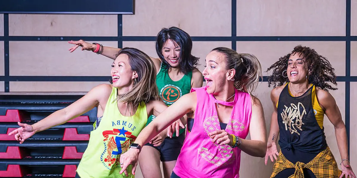 A group of smiling women in brightly dressed active wear dancing during a Zumba class at Christchurch Recreation and Sport.