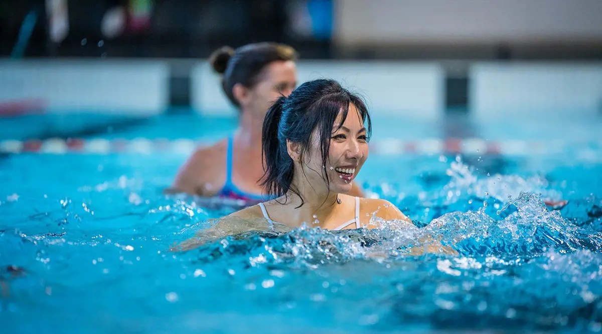 Two women smiling in the pool while participating in an Aqua jogging class at a Christchurch Recreation and Sport pool.