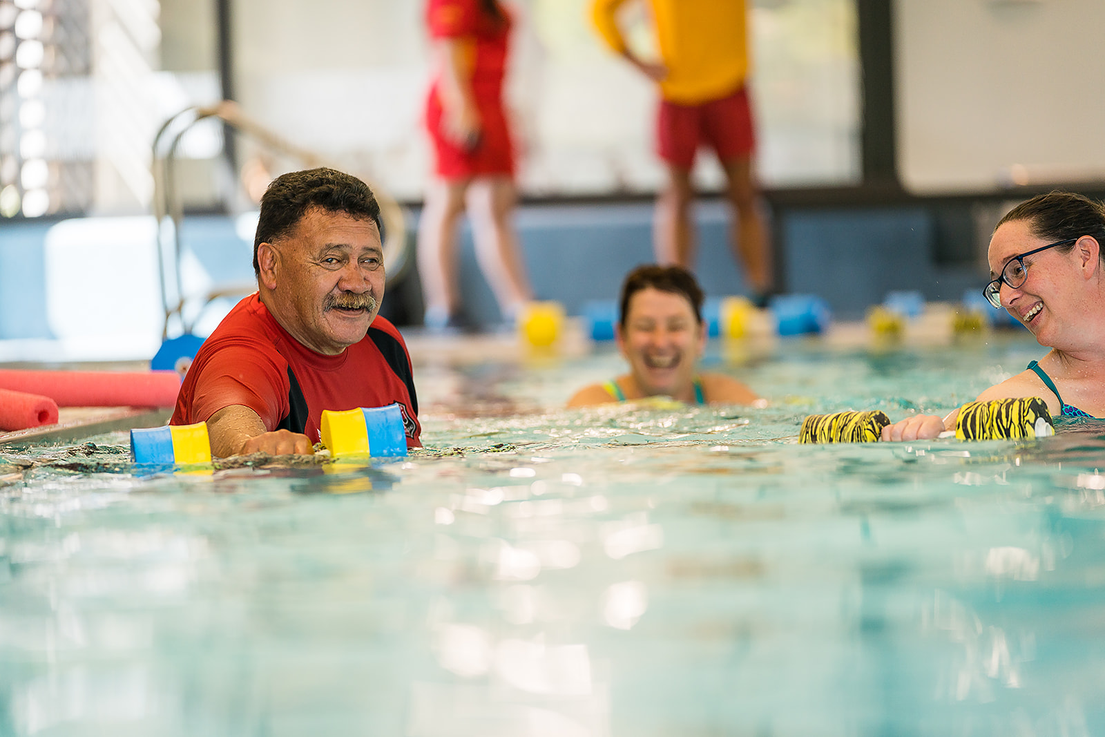 Two women and a man holding flotation dumbbells participating in an Aqua gentle class at Christchurch Recreation and Sport pool. 