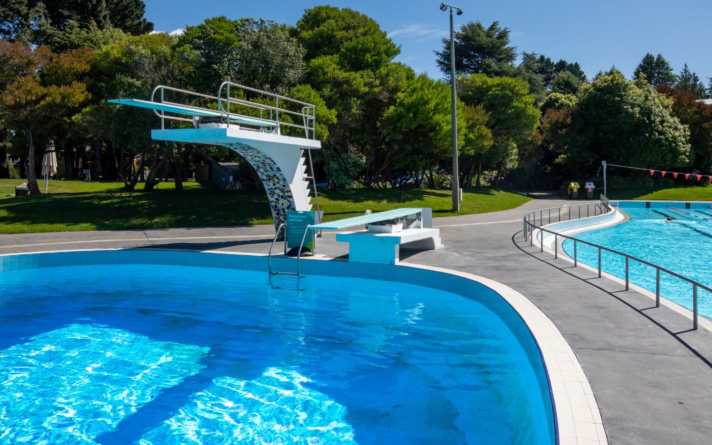 Two white diving board on the pool deck of a Christchurch outdoor summer pool. 