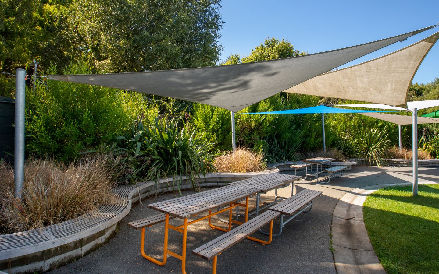 Park benches under shade covers at a Christchurch outdoor summer pool. 