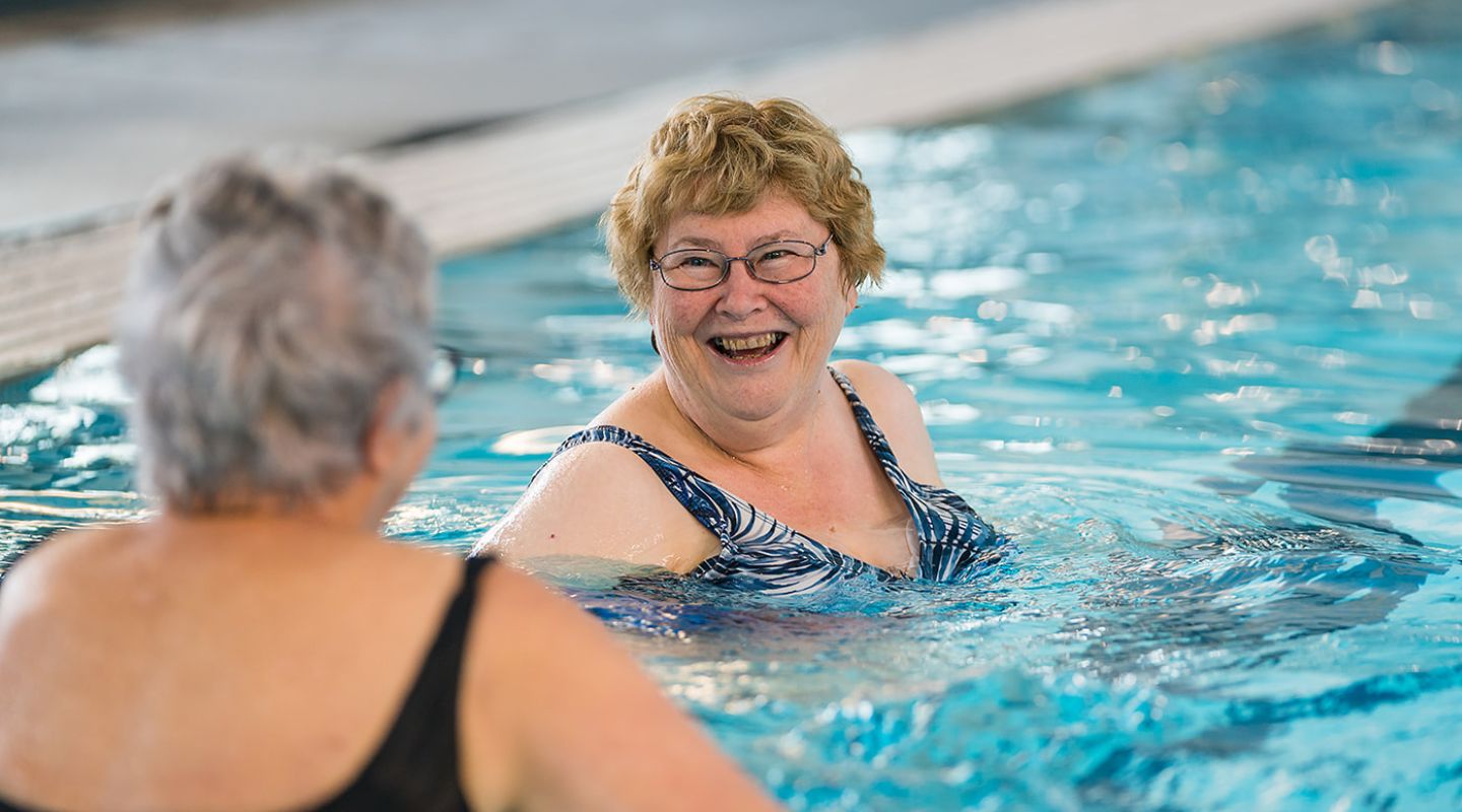 Two older women smiling in the pool while participating in an Aqua gentle class at Christchurch Recreation and Sport pool