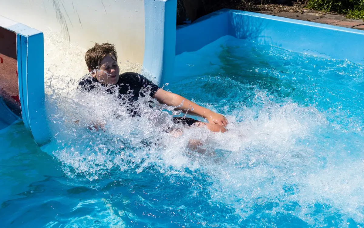 A smiling boy sliding down the Halswell Summer Pool hydroslide.