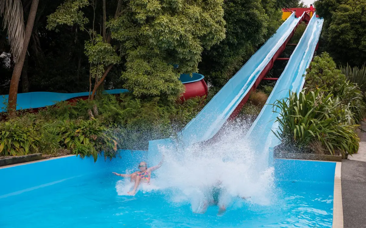 Children racing down the tandem blue hydroslides at Jellie Park Recreation and Sport Centre outdoor pool.