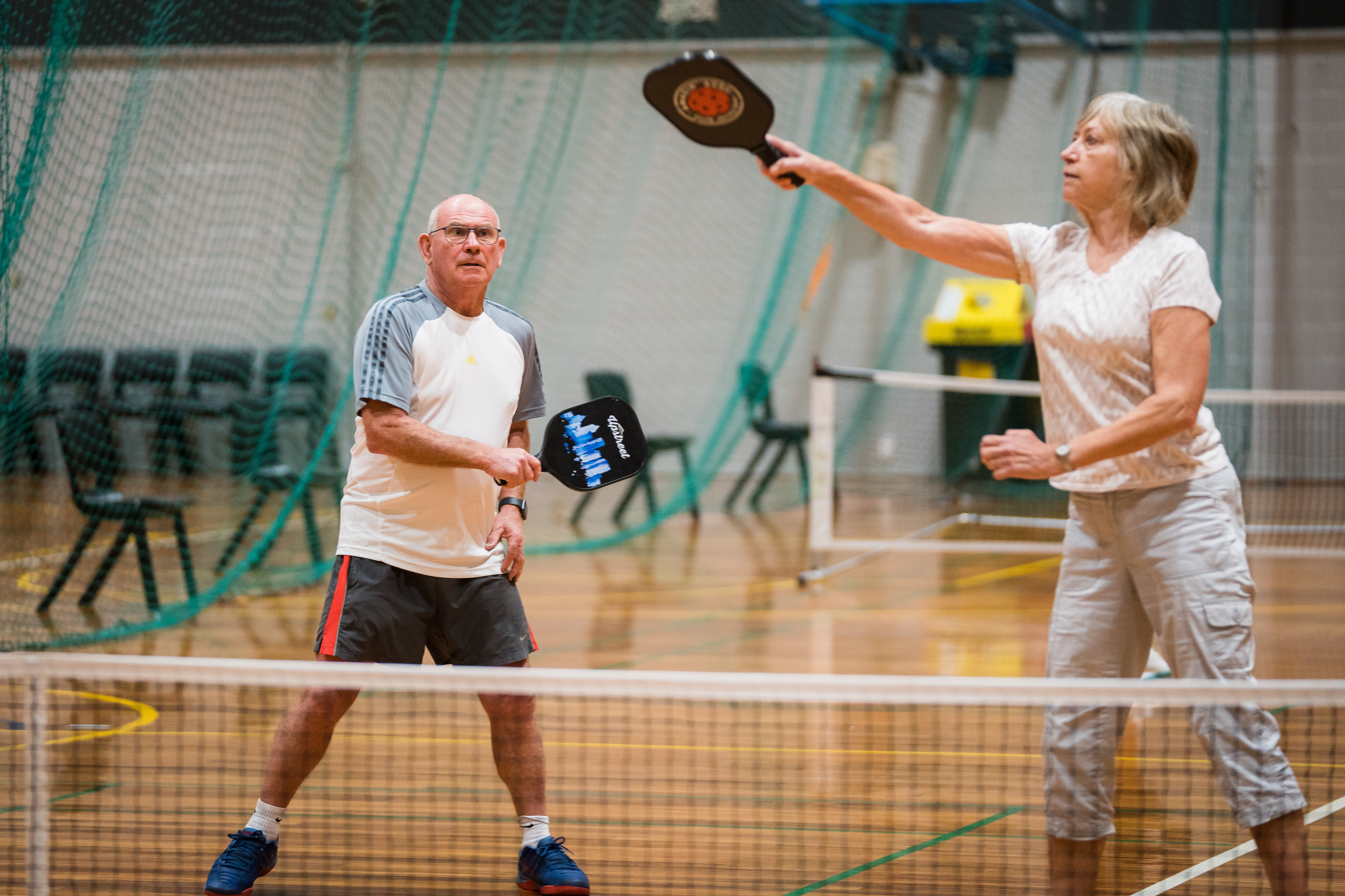A woman hitting an orange ball while playing pickleball at Christchurch Recreation and Sport centre. 